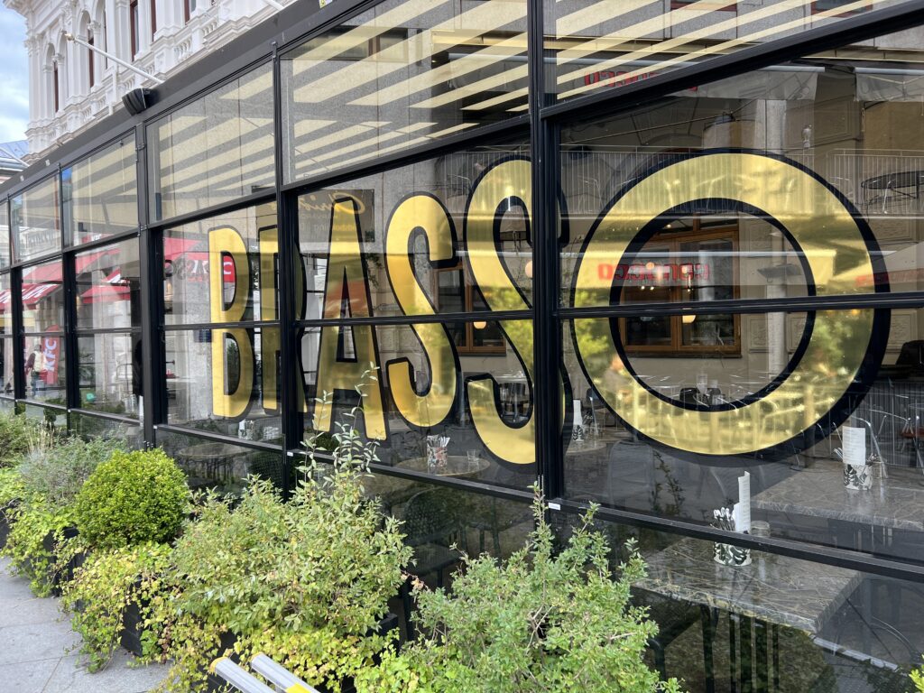 Glasdekor för restaurang Brasso i högblank guldvinyl med svart outline.