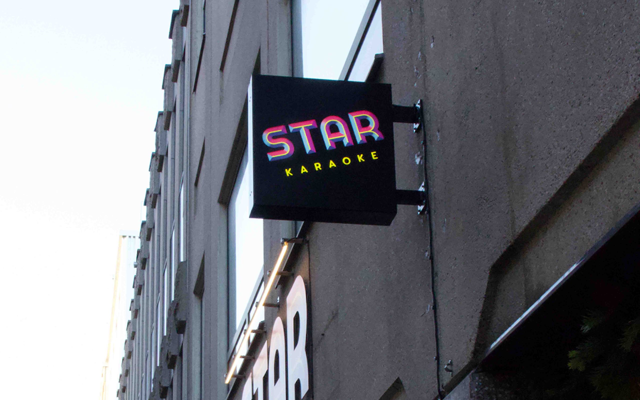 Flaggskylt vid Star Karaoke i Göteborg. Kvadratisk svartlackerad skylt med logotypen på båda sidor.