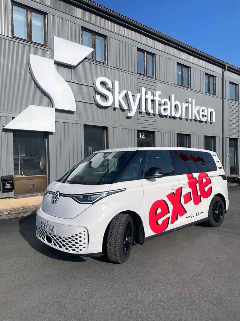 EX-TE bildekor på Volkswagen ID Buzz. Logotype i röd vinylfolie monterad på snedden över sida på bil.