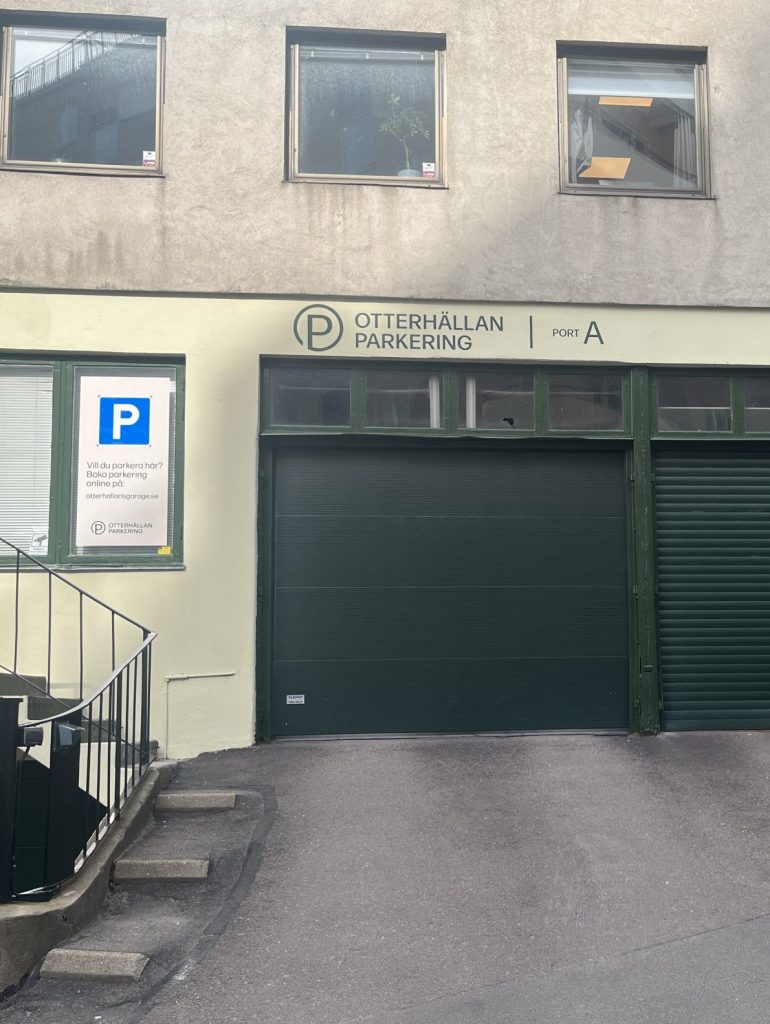 En skylt behöver inte bara visa vägen, den kan också bli ett komplement till en byggnad, en entré eller som här – Fasadskyltar för Otterhällans garage. Infarten till parkeringen pryds nu av en vacker mörkgrön shablonmålad text.