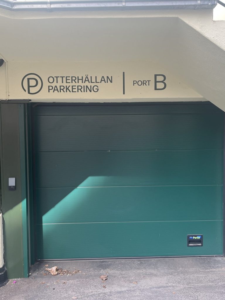 En skylt behöver inte bara visa vägen, den kan också bli ett komplement till en byggnad, en entré eller som här – Fasadskyltar för Otterhällans garage. Infarten till parkeringen pryds nu av en vacker mörkgrön shablonmålad text.