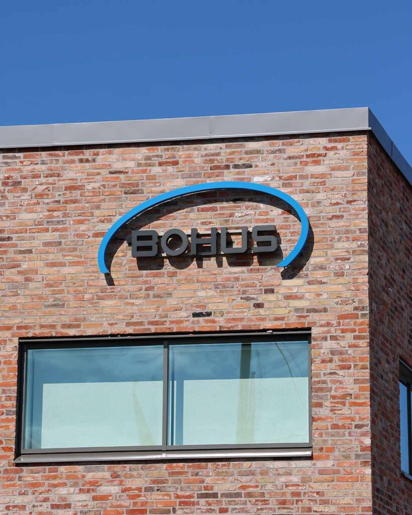 Fasadskylt för Bohus ombyggda fastighet på Exportgatan, Hisings Backa. Blå och svart fasadskylt där de svarta tecknen lyser med vit ljuseffekt på natten.