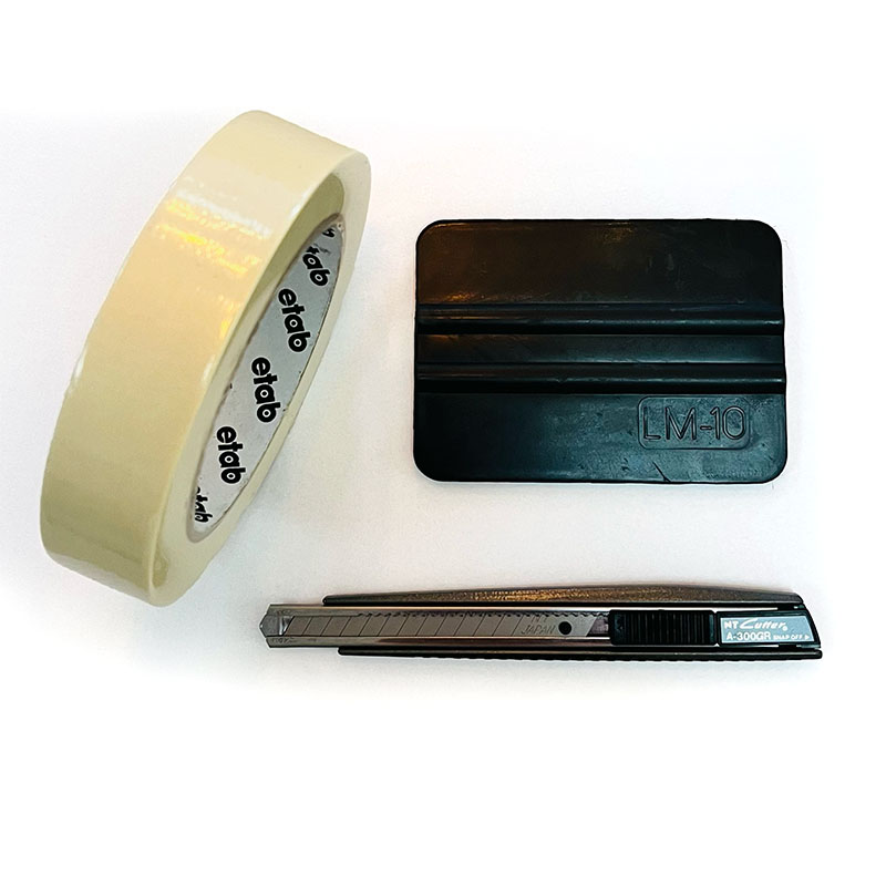 Ett litet verktygsset med tejp, brytbladskniv och gummiskrapa som är bra att ha vid montage av foliedekor till exempel foliedekor.